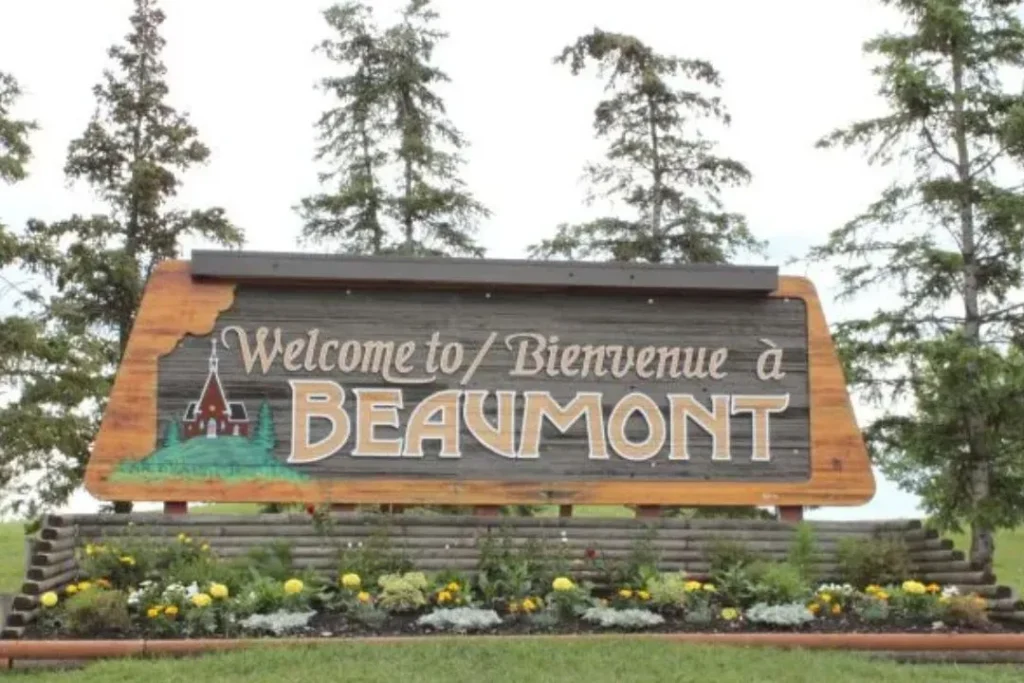 Wooden welcome sign at the entrance to Beaumont, Alberta – bilingual greeting with trees in background