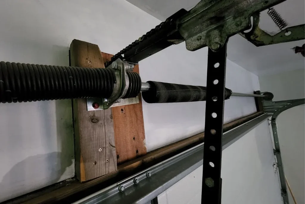 Garage door torsion spring system securely mounted on wooden support